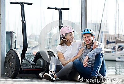 Couple sitting near segways at sea front Stock Photo