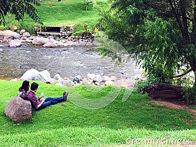 Couple sitting on River Bank of Rio Tomebamba in Cuenca, Ecuador Editorial Stock Photo