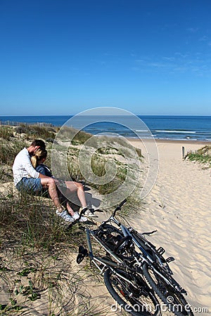 Couple sitting on sandy dune embracing Stock Photo