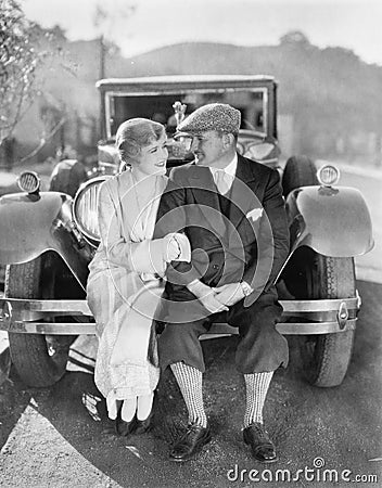 Couple sitting together on a car bumper Stock Photo