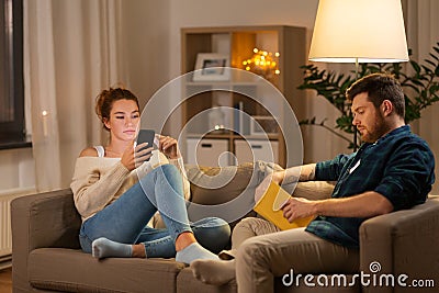 Couple with smartphone and book at home Stock Photo