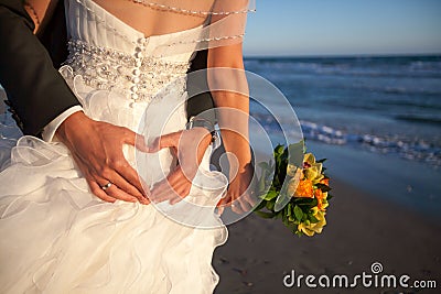 Couple smiling and embracing near wedding arch on beach. Honeymoon on sea or ocean Stock Photo