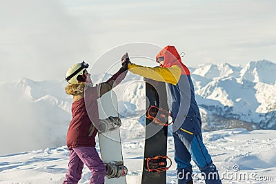 Couple snowboarding freeriders man and a woman give five with snowboards Stock Photo