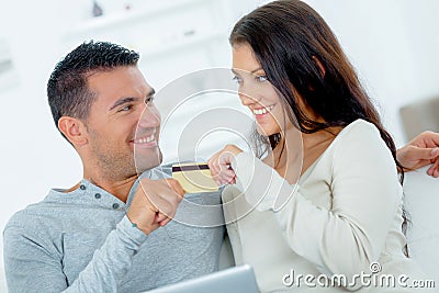 Couple on sofa both clutching same credit card Stock Photo