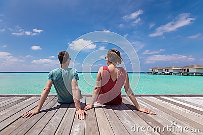 Couple spending romantic beach vacation holidays at luxurious resort in Maldives with turquoise sea water, blue sky and overwater Stock Photo