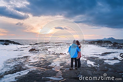 A couple standing on the frozen rock and ice beside the sea Stock Photo