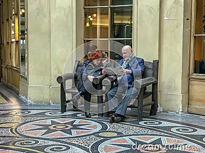 A couple studies Streetwise Paris while resting on a bench Editorial Stock Photo