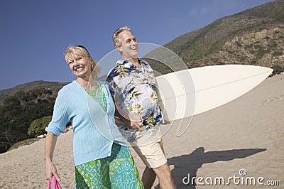 Couple with surfboard smiling on beach Stock Photo
