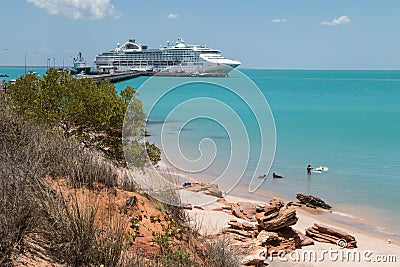 Couple swimming with dogs modern cruise ship tied up to jetty surrounded by a turquoise sea in the background at Broome in Western Stock Photo