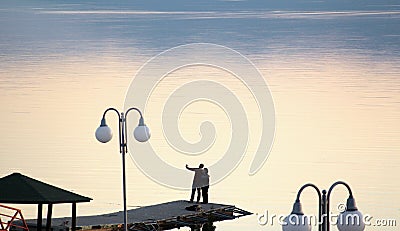 Couple takes selfy on a pier on a lake prespa in macedonia.sunset over lake . Stock Photo