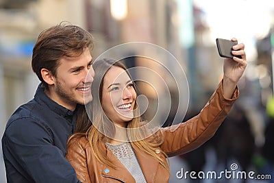 Couple taking selfie photo with a smart phone in the street Stock Photo