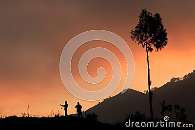 A couple taking shots of sunset using a handphone and a camera Stock Photo