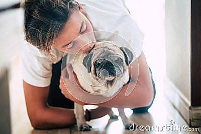 Couple of teenager and cute white pug - love and affection of two best frieds at home - loving the animals Stock Photo