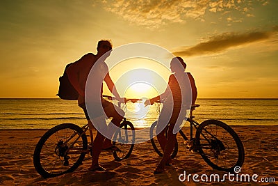 Couple tourists with Bicycles Watching Sunset. Silhouette people Stock Photo