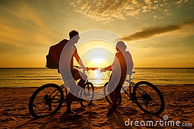 Couple tourists with Bicycles Watching Sunset. Silhouette people Stock Photo