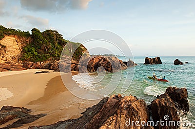 Couple tourists kayaking in tropical sea in the evening. Beautiful curved bay, beach, stone, rocks and waves. Fishermen and sunset Stock Photo