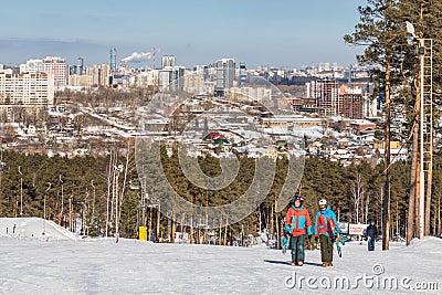 A couple in tracksuits and with snowboards walk to the top of the training slope of the sports complex on Mount Uktus, Editorial Stock Photo