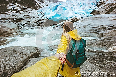 Couple travelers follow holding hands in mountains glacier Stock Photo