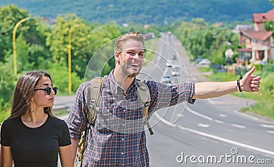 Couple travelers man and girl hitchhiking at edge road nature background. Travel by autostop. Couple hitchhikers Stock Photo