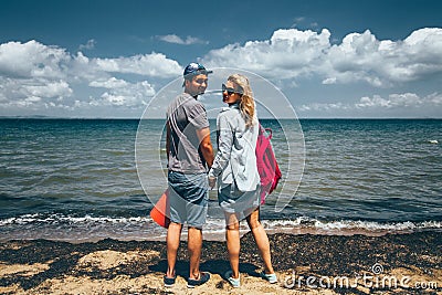 Couple Travelers Man And Woman Standing On Seashore And Looks At The Camera Adventure Travel Journey Concept Stock Photo