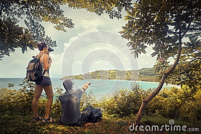 Couple travellers with backpacks watching through binoculars enjoying view coast Stock Photo