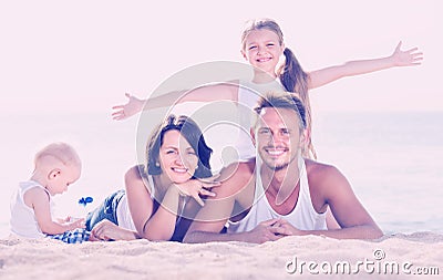 Couple with two children lying on beach Stock Photo