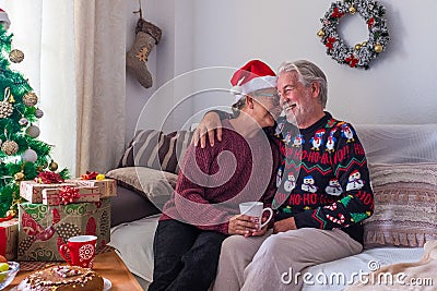 Couple of two happy seniors and mature people sitting in the sofa having fun together wrapping the gifts and presents - pensioners Stock Photo