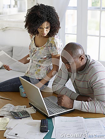 Couple Using Laptop With Bills Stock Photo