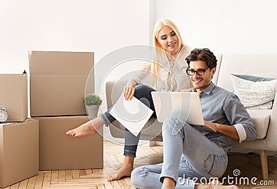 Couple using laptop reading certificate of property on couch Stock Photo