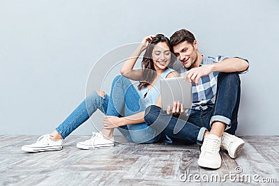 Couple using tablet sitting on the floor at home Stock Photo