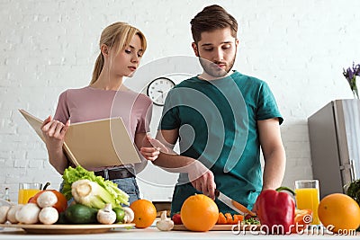couple of vegans preparing food with recipe book Stock Photo