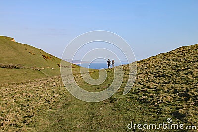 A couple walk in a dip in the hills at Seatown in Dorset, situated on the coastal path on the Jurassic coast between Charmouth and Stock Photo