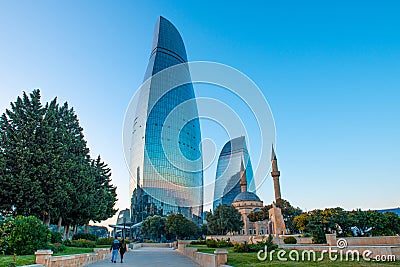 Couple walk with Flame towers in the cityscape in background. Panoramic view of Baku - the capital of Azerbaijan located by the Editorial Stock Photo