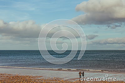 A couple walking on the beach in Brora village in Scotland, UK Stock Photo