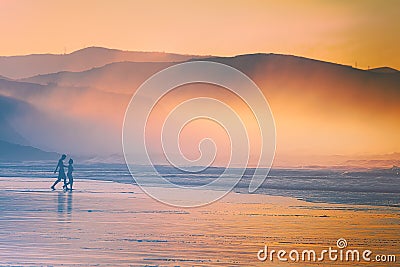 Couple walking on beach at sunset Stock Photo