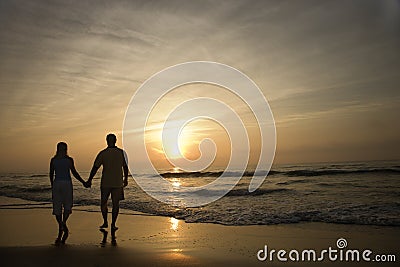 Couple Walking on Beach at Sunset Stock Photo