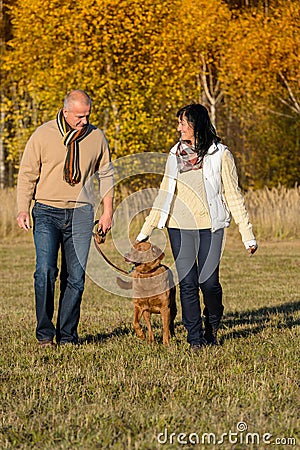 Couple walking dog in autumn sunny park Stock Photo