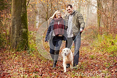 Couple Walking Dog Through Winter Woodland Stock Photo