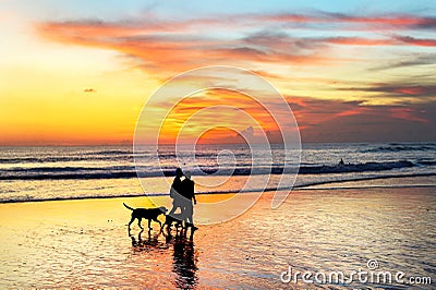 couple walking dogs, sunset Bali Stock Photo
