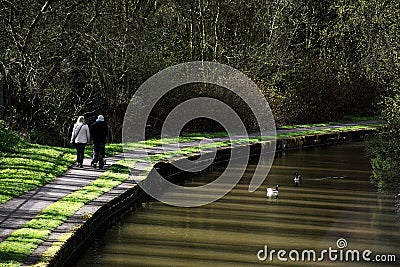 Couple walking on path near canal in spring. Stock Photo