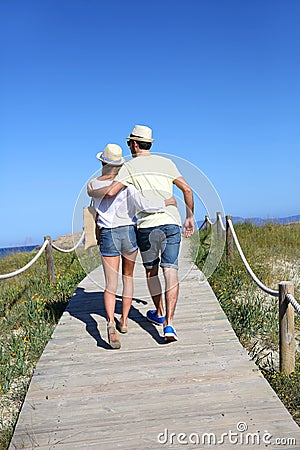 Couple walking on wooden pontoon going to the beach Stock Photo