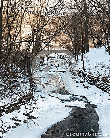 Couple walks along frozen creek in a park Stock Photo