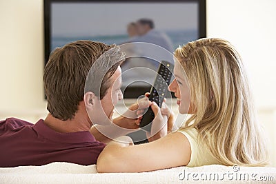 Couple Watching Widescreen TV At Home Stock Photo