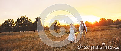 Couple in wedding attire against the backdrop of the field at sunset, the bride and groom. Stock Photo