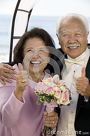 Couple at wedding giving thumbs-up smiling (portrait) Stock Photo