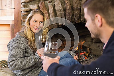 Couple with wineglasses in front of lit fireplace Stock Photo