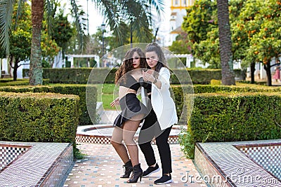 Couple of young women dancing to different types of Latin music and dance. The two girls do different postures dancing outdoors in Stock Photo