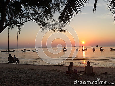 Couples swing watching the sunset,Some people sit on the beach listening to music. Editorial Stock Photo