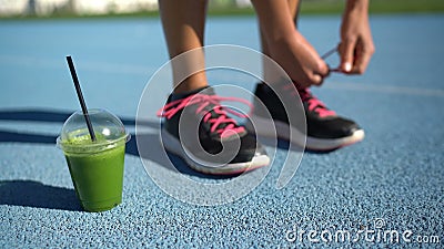 Coureur femelle attachant des chaussures pour la piste fonctionnant avec une tasse de smoothie vert du petit déjeuner clips vidéos Coureur femelle attachant des chaussures pour la piste fonctionnant avec une tasse de smoothie vert du petit déjeuner clips vidéos