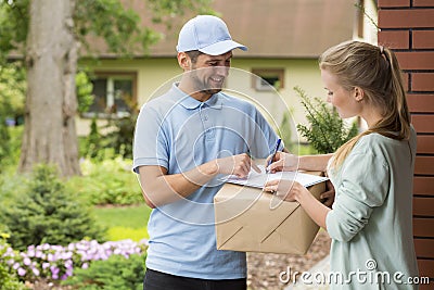 Courier holding a parcel and woman signing a delivery form Stock Photo